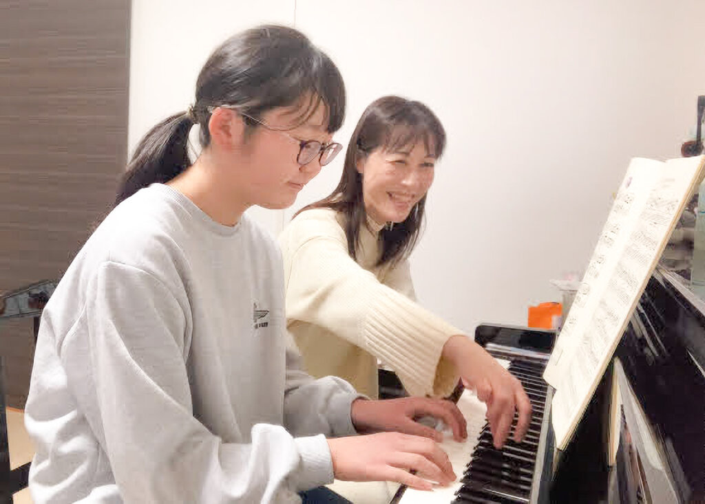 笑顔で楽しくピアノを教えている講師と生徒